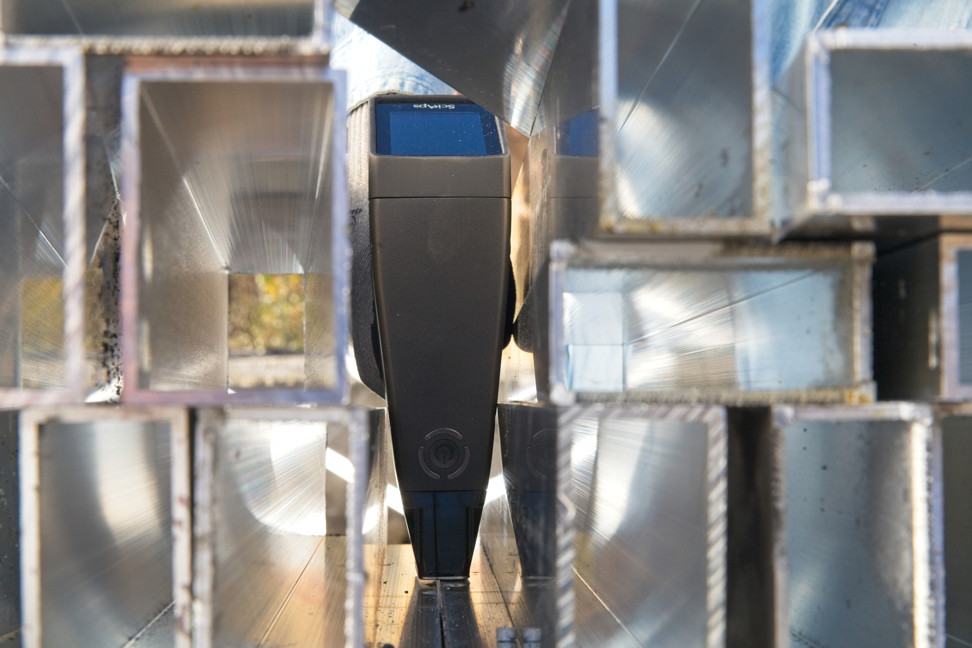 Handheld-XRF-Gerät misst ein Stahl-Hohlprofil im Lager zur Legierungsidentifikation